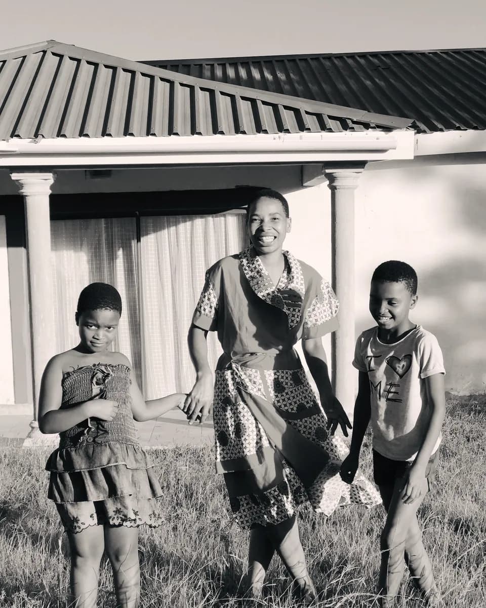 A mother smiling with her children in a sunny backyard