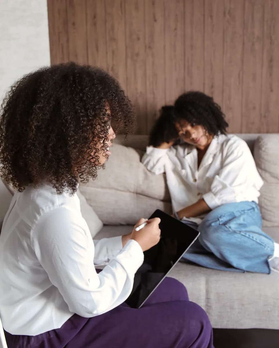 Two women sitting together on a sofa, talking with care and trust